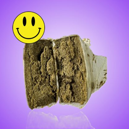 Close-up view of golden-brown static hash, showcasing its crumbly texture and rich, resinous surface. The hash is finely sifted, with a slightly glossy appearance that reflects light, indicating high potency and quality.